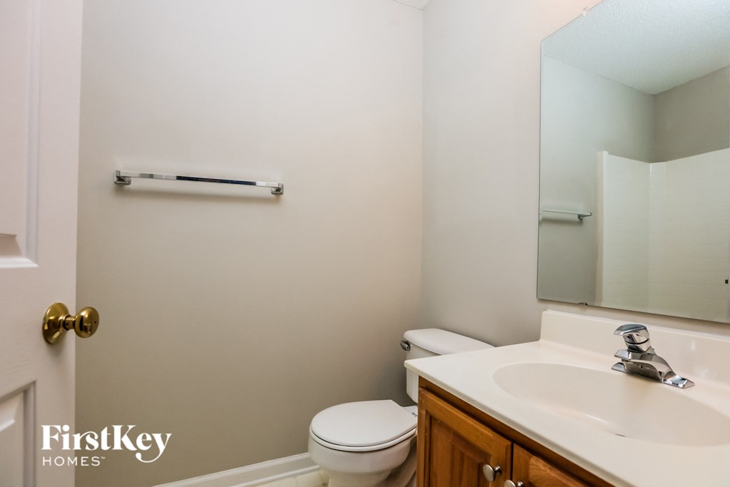 A white toilet sits in a small bathroom with a white sink and a mirror.