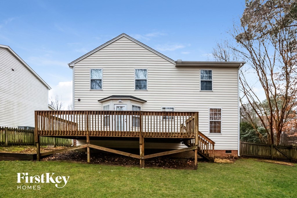 A white house with a deck in front of it.