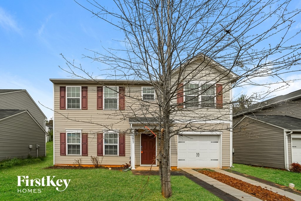 A house with a bare tree in front of it.