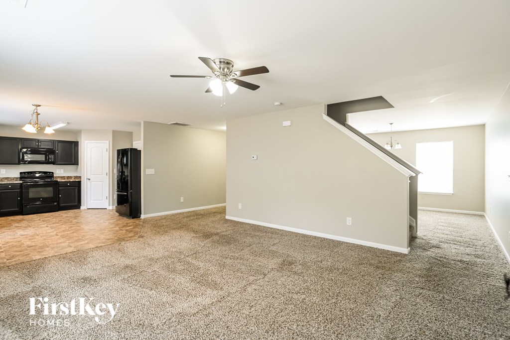 A spacious living room with a staircase on the right side.