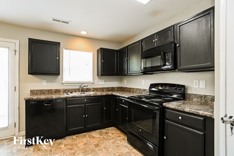 A kitchen with black cabinets and appliances.