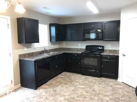 A kitchen with black cabinets and a black stove top oven.