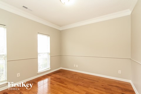 a living room with wood floors and white walls and a window