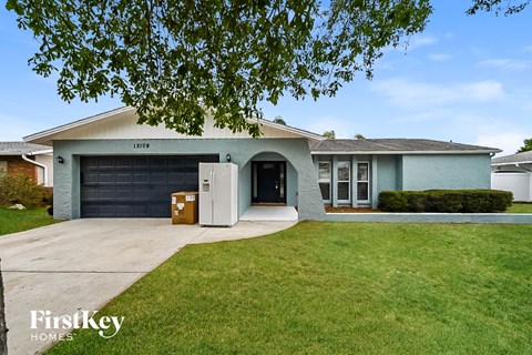 a blue house with a driveway and a black garage door