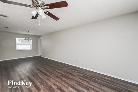 the living room of an empty house with a ceiling fan