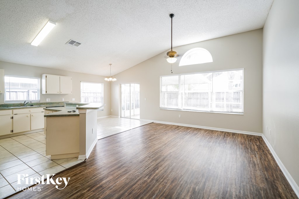 A spacious kitchen and living room with wooden floors and white walls.