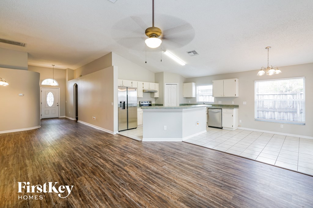 A spacious living room with wood flooring and a ceiling fan.