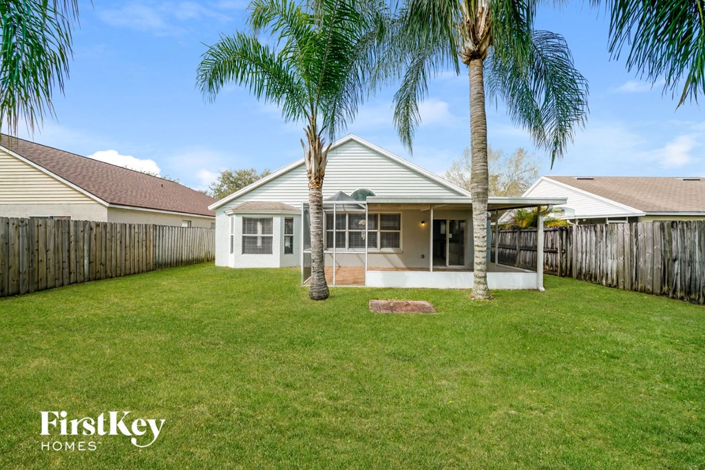 A house with a lawn and two palm trees in front.