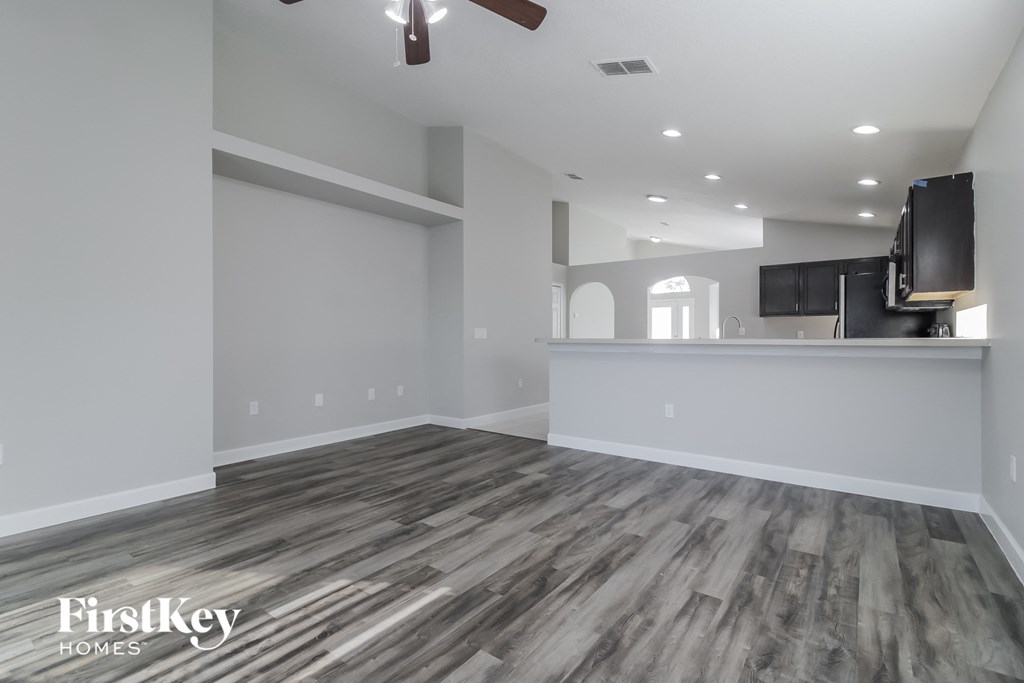 a renovated living room with a kitchen and grey flooring