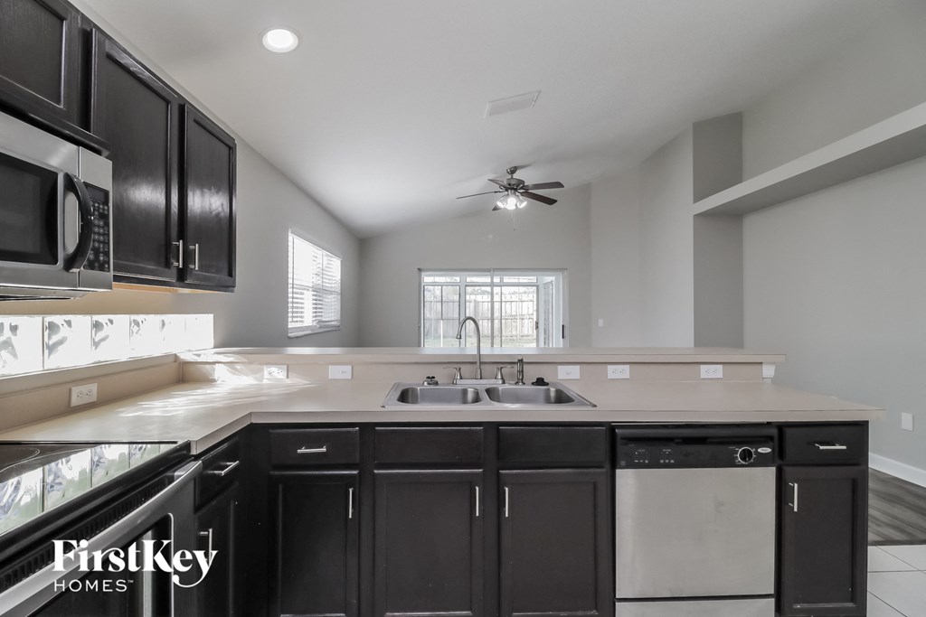 a kitchen with black cabinets and white counter tops and a sink