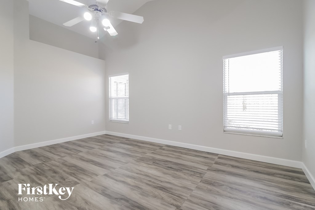 the spacious living room with wood flooring and a ceiling fan
