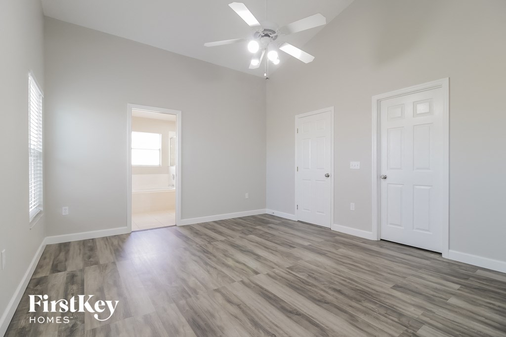 an empty living room with a ceiling fan and white doors