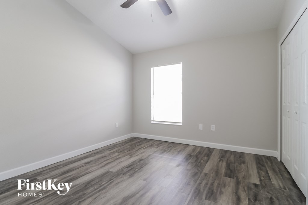 the living room with wood flooring and a ceiling fan