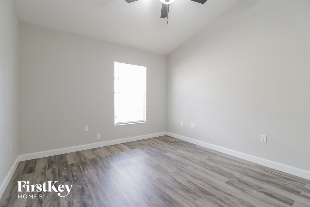 the living room with wood floors and white walls and a window