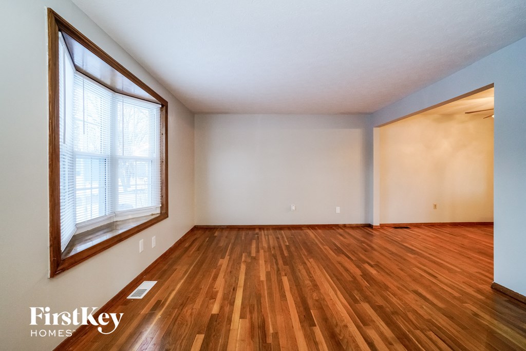 the living room of an empty house with wood floors and a large window