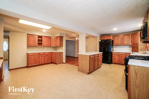 a kitchen with wooden cabinets and a black refrigerator