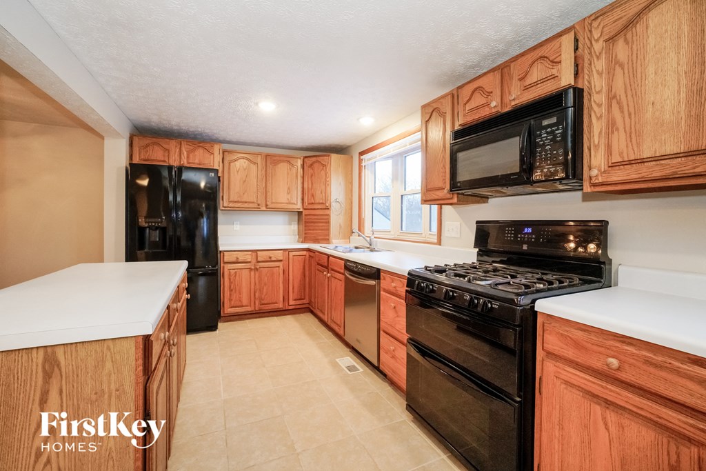 a kitchen with black appliances and wooden cabinets and white counter tops