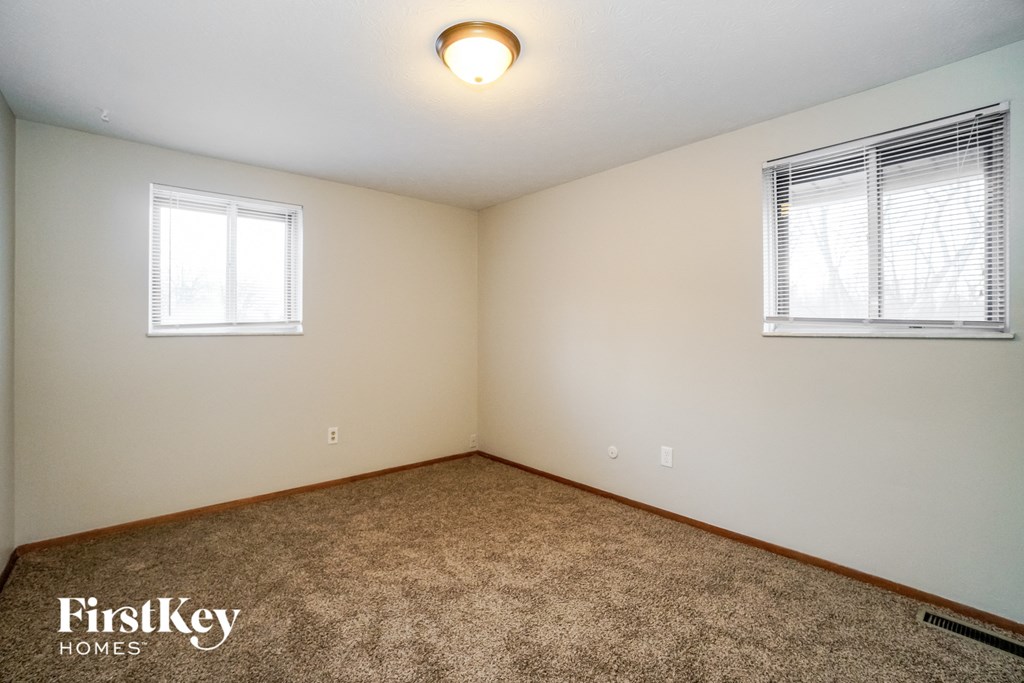 the living room of an empty house with carpet and two windows