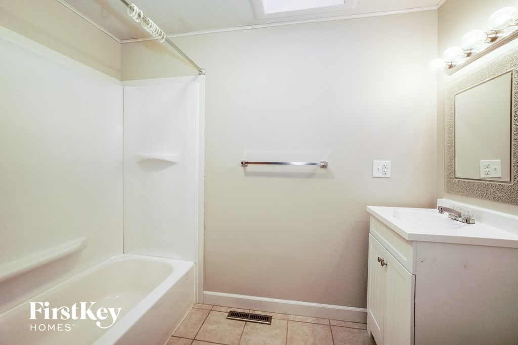 a white bathroom with a tub and a sink and a mirror