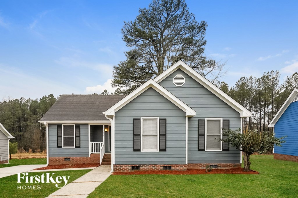 front view of a blue house with a lawn and trees