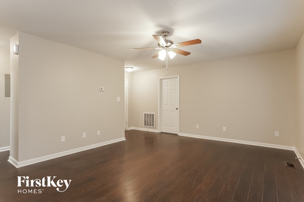 an empty living room with wood floors and a ceiling fan