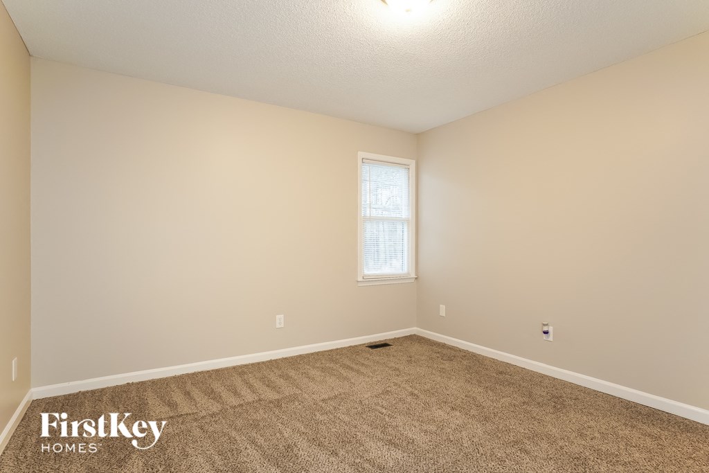 the spacious living room with carpeting and a window