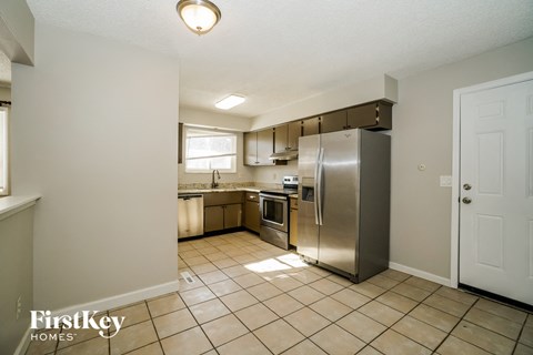 A kitchen with a stainless steel refrigerator and a tile floor.