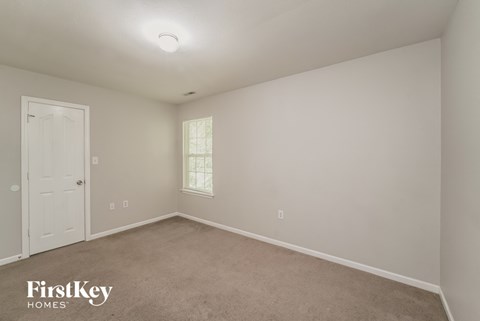 a bedroom with white walls and carpet and a white door