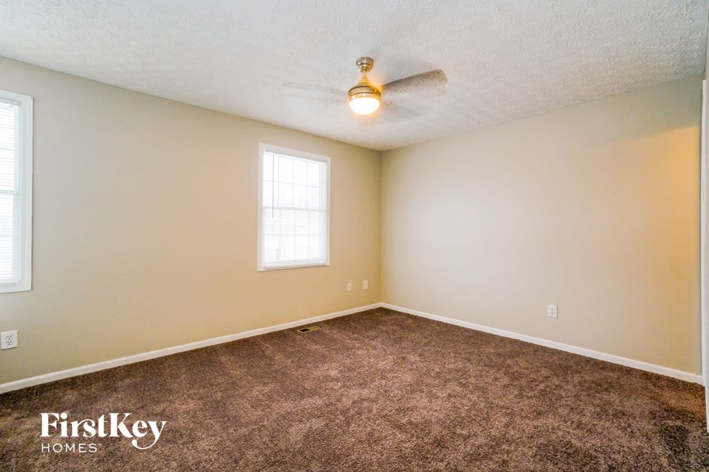 a carpeted room with a ceiling fan and a window