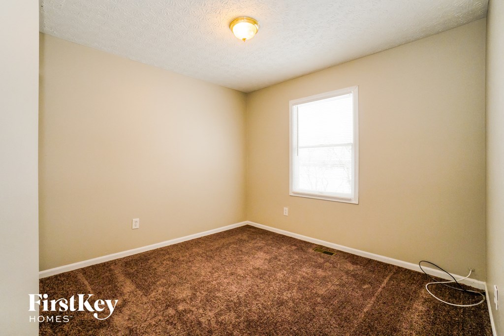 the upstairs bedroom with carpet and a window