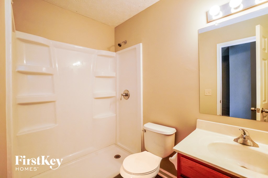 a bathroom with a shower toilet and sink and a mirror
