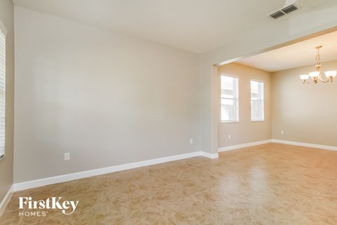 A spacious room with a chandelier and two windows.