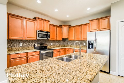 A kitchen with orange cabinets and granite countertops.