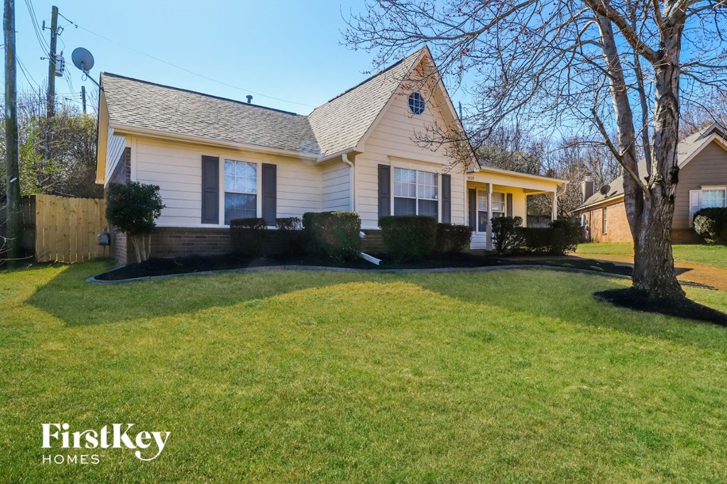 a white house with a lawn and a tree