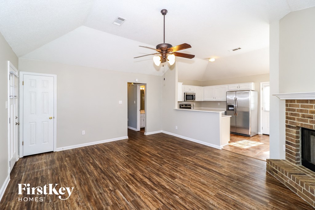 an empty living room with a fireplace and a ceiling fan