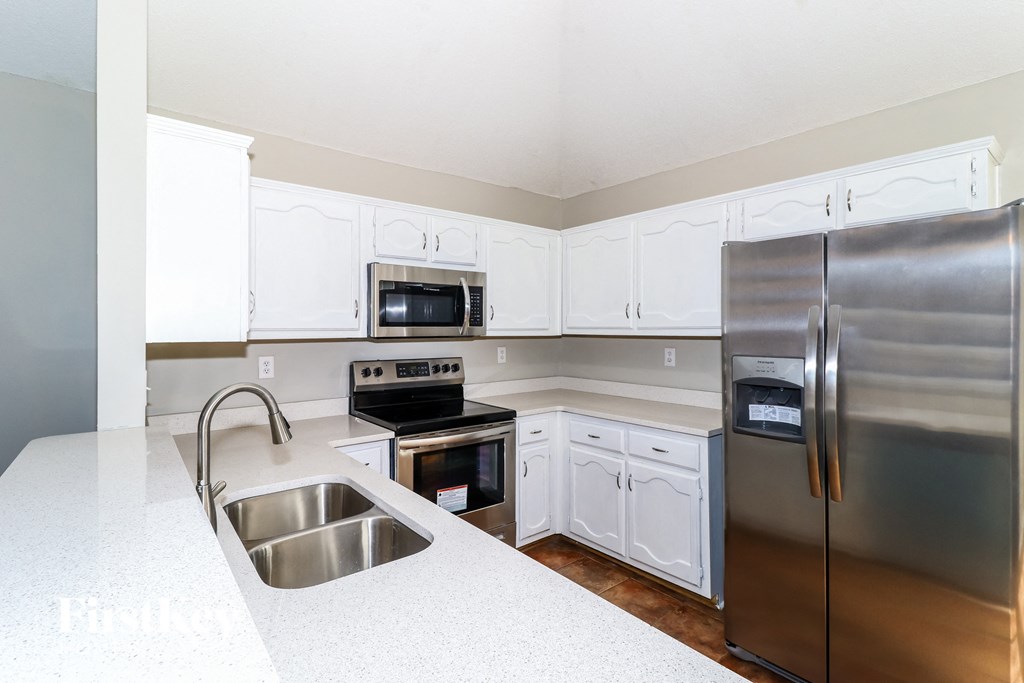 a kitchen with white cabinets and stainless steel appliances