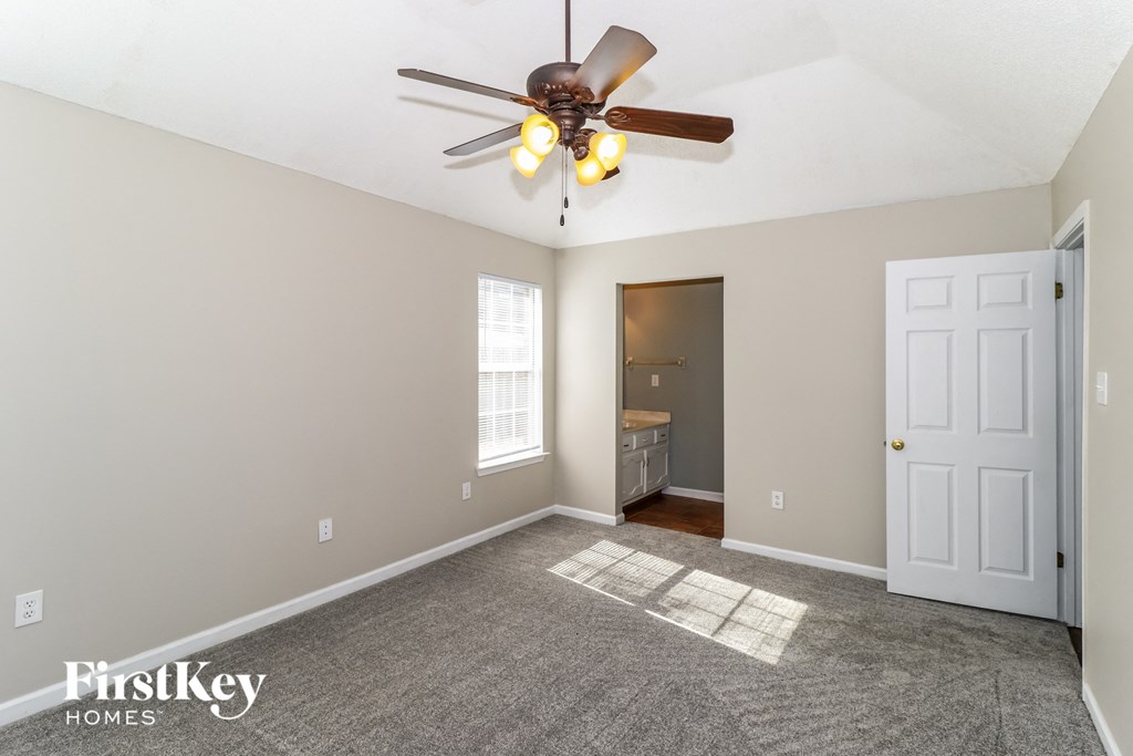 a living room with a ceiling fan and a door to a bathroom