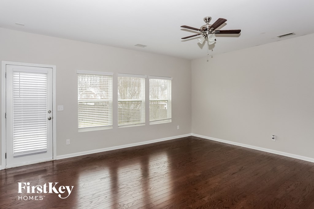 A room with a ceiling fan and wooden floors.