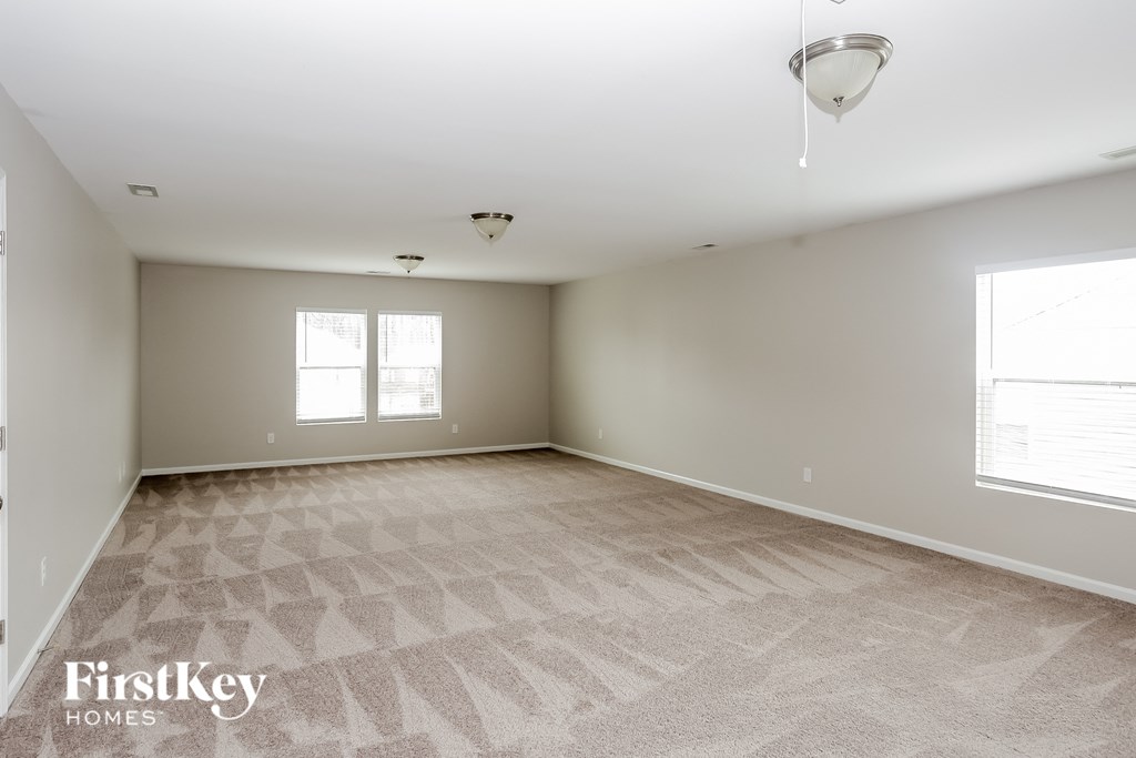 A spacious room with a carpeted floor and a window.