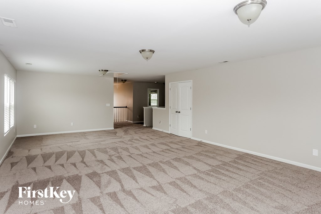 A spacious room with a carpeted floor and a white ceiling.