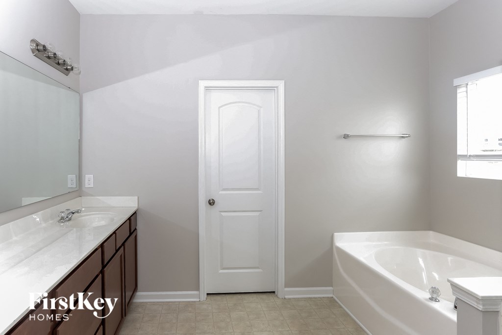 A white bathroom with a tub, sink, and mirror.