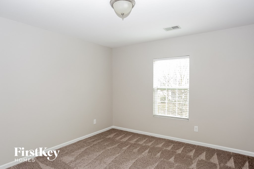A room with a carpet floor and a window with blinds.
