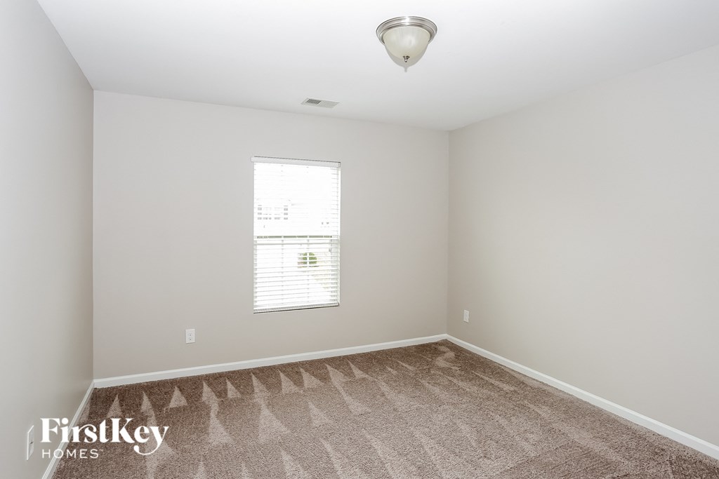A room with a carpeted floor and a window with blinds.