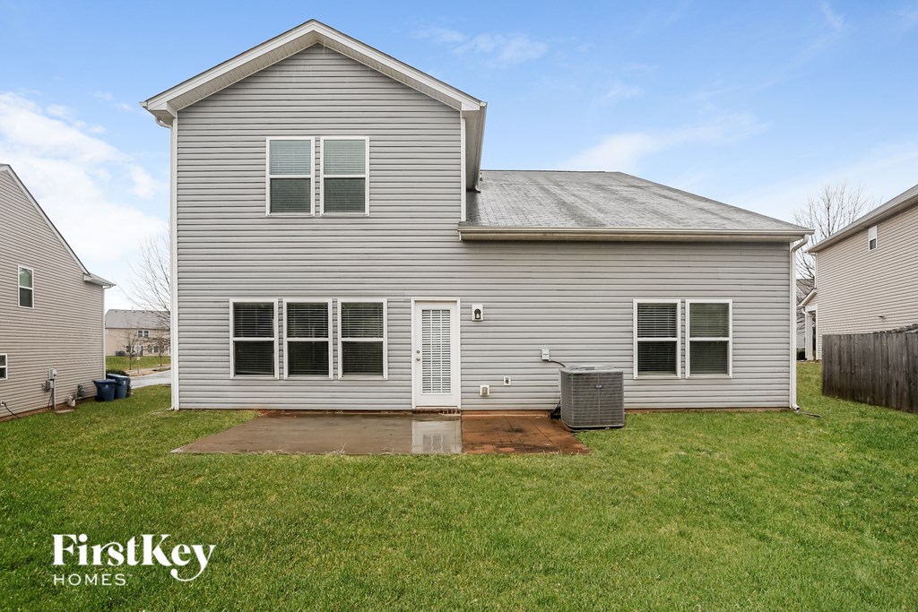 A grey house with a white door and windows is for sale.