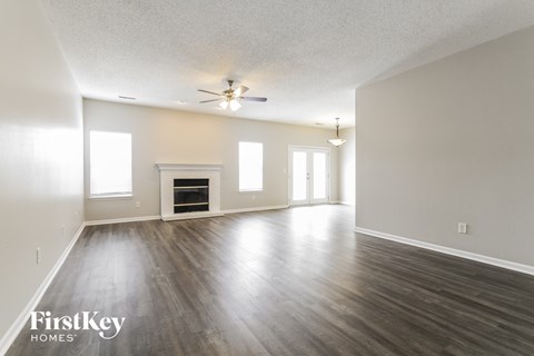 an empty living room with a ceiling fan and a fireplace