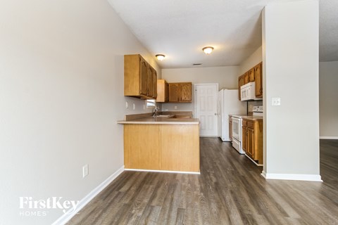 a kitchen with wood flooring and wooden cabinets and a white refrigerator