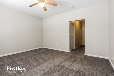 a living room with carpet and a ceiling fan