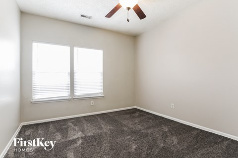 a bedroom with carpet and two windows and a ceiling fan