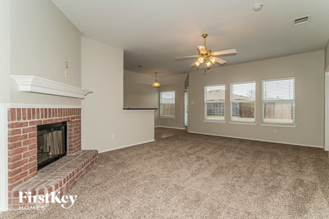 a living room with a brick fireplace and a ceiling fan