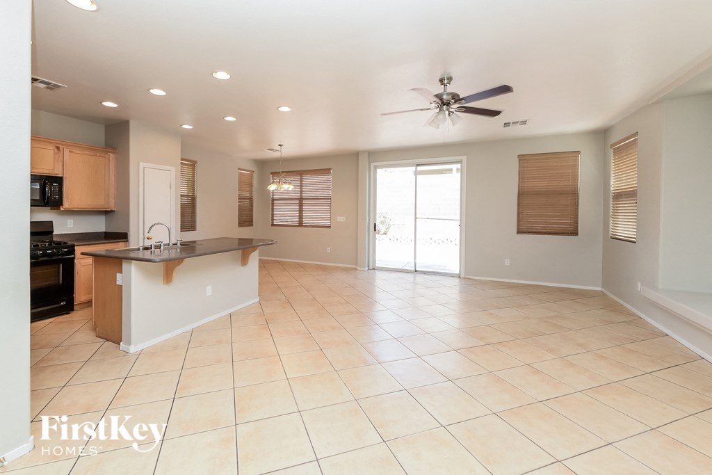 an open kitchen and living room with tile flooring and a ceiling fan